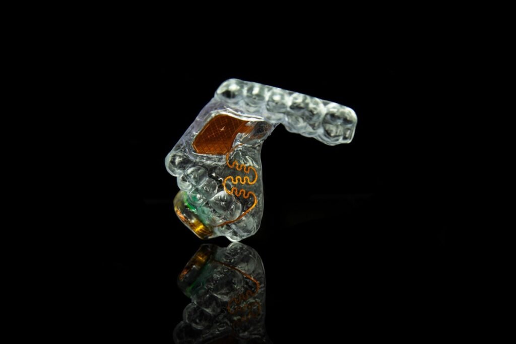 Retenedor dental transparente MouthPad de Augmental mostrado en su estuche de carga USB-C.