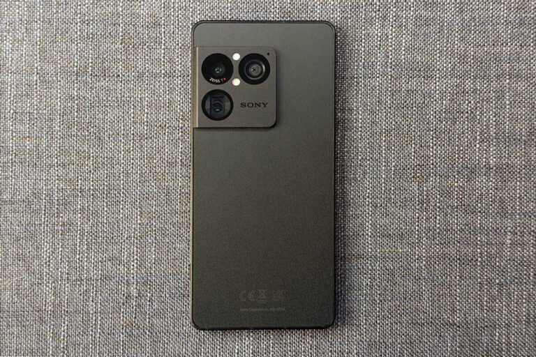 Vista frontal de la pantalla OLED encendida de el Sony Xperia 1 VIII junto a unos auriculares de cable conectados a su puerto superior de 3,5 mm.