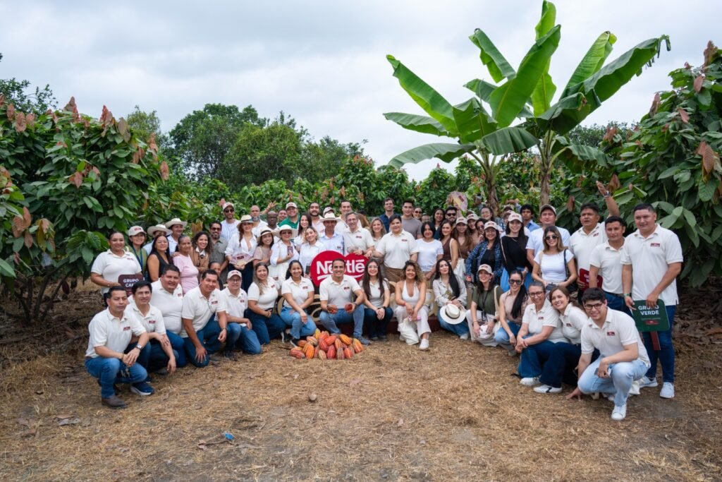Productores agrícolas ecuatorianos sonriendo en una plantación sosteniendo frutos recolectados de alta calidad, representando el futuro del cacao ecuatoriano.