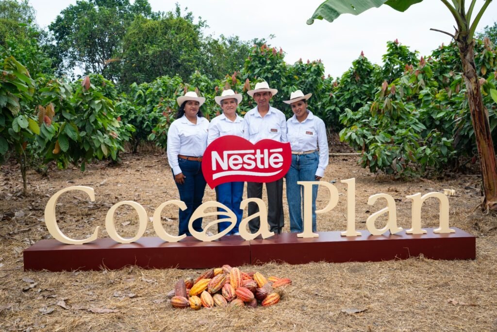 Productores agrícolas ecuatorianos sonriendo en una plantación sosteniendo frutos recolectados de alta calidad, representando el futuro del cacao ecuatoriano.