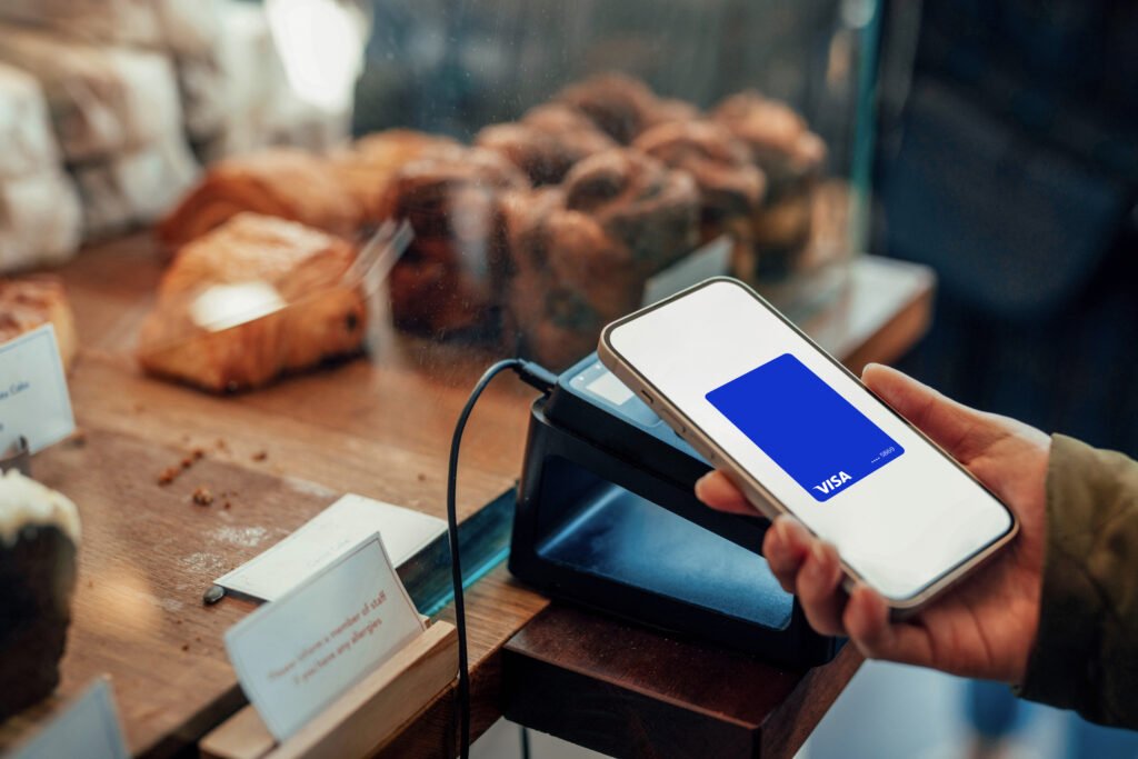 Vista en primer plano de un usuario sosteniendo una tarjeta de crédito frente a un computador con alertas de seguridad digital, ilustrando la prevención contra los intentos de fraude digital.