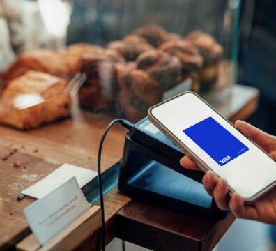 Vista en primer plano de un usuario sosteniendo una tarjeta de crédito frente a un computador con alertas de seguridad digital, ilustrando la prevención contra los intentos de fraude digital.