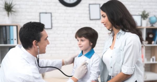 Niño sonriendo mientras realizan un chequeo médico preventivo durante las vacaciones escolares