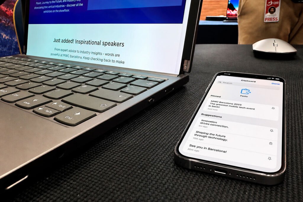 Un iPhone junto a un ordenador representando la interoperabilidad entre iPhone y Windows para copiar y pegar archivos.
