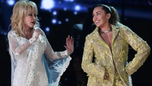 Fotografía de la cantante Miley Cyrus junto a su madrina previa al análisis sobre el futuro del patrimonio musical de Dolly Parton tras su fallecimiento.