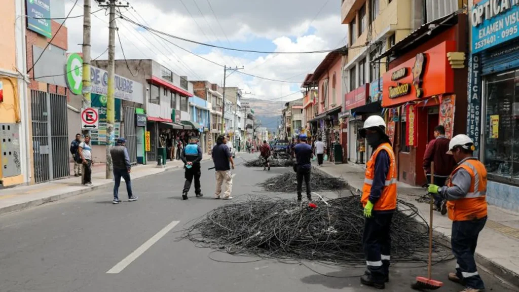 Tecnicos retirando rollos de cables en desuso en postes del barrio Cotocollao en Quito