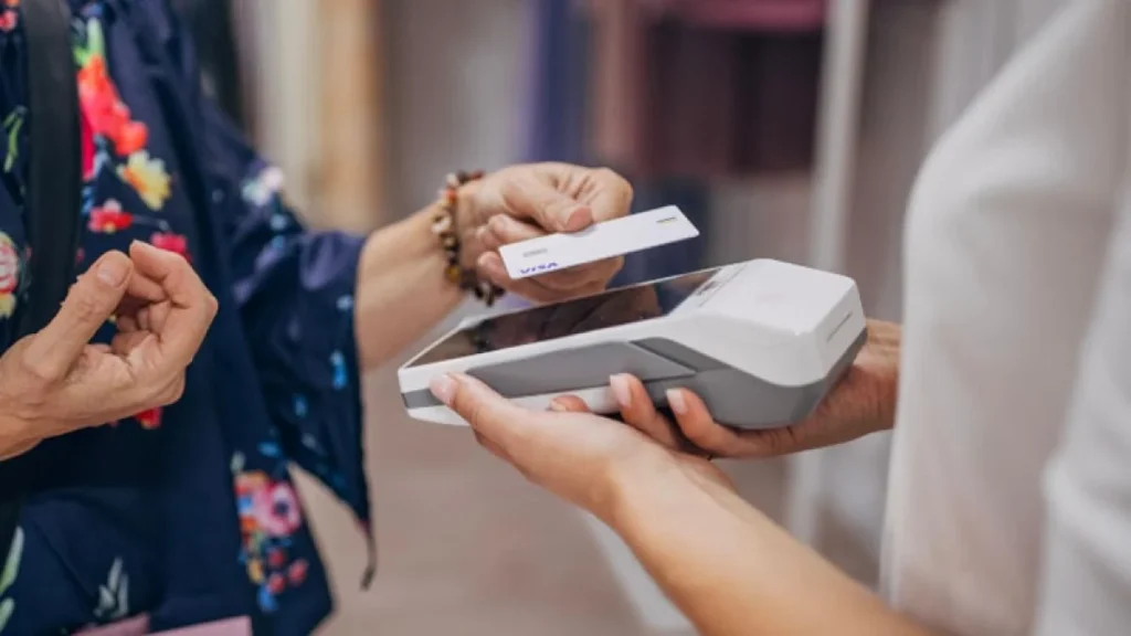 Usuario realiza pago electrónico sin contacto con tarjeta en terminal comercial