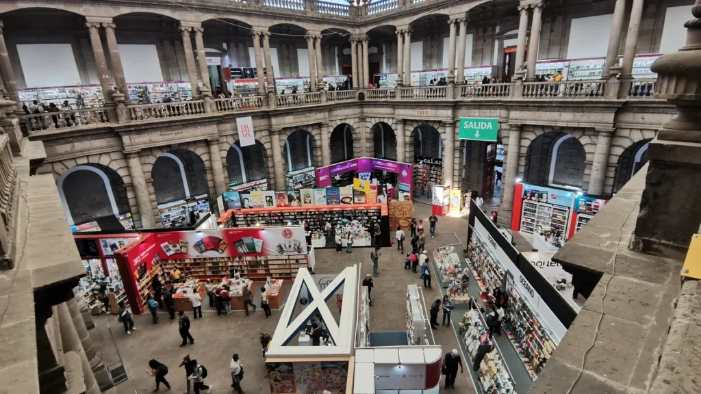 Patio de una feria del libro con público recorriendo los stands de editoriales
