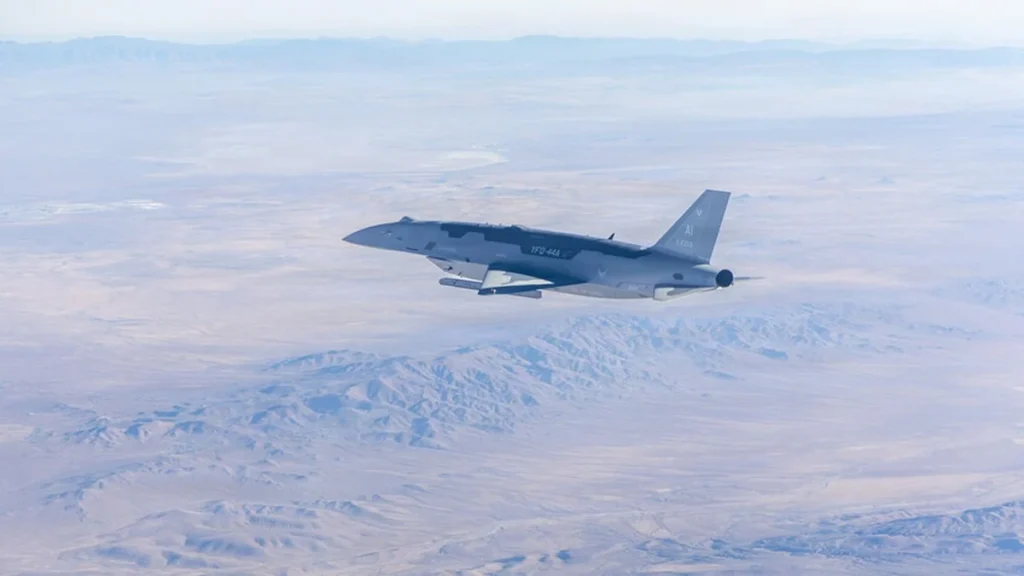 Caza furtivo F-22 volando en formación junto a un avión no tripulado de combate.