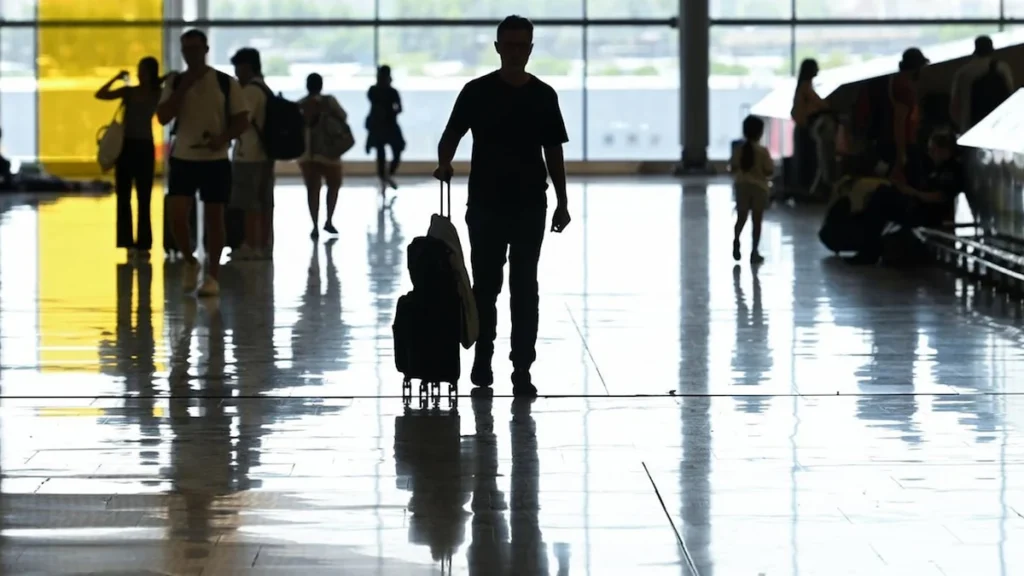 Pasajeros esperando en pantallas de salidas de vuelos en aeropuerto de Italia