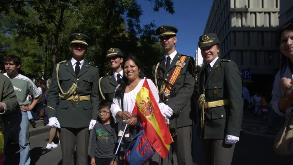 Familia migrante boliviana observando el desfile militar del 12 de octubre en Madrid