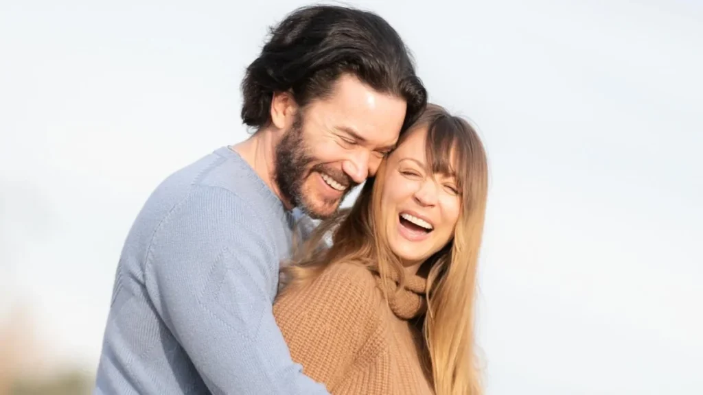 Kaley Cuoco sonriendo junto a Tom Pelphrey en un retrato familiar
