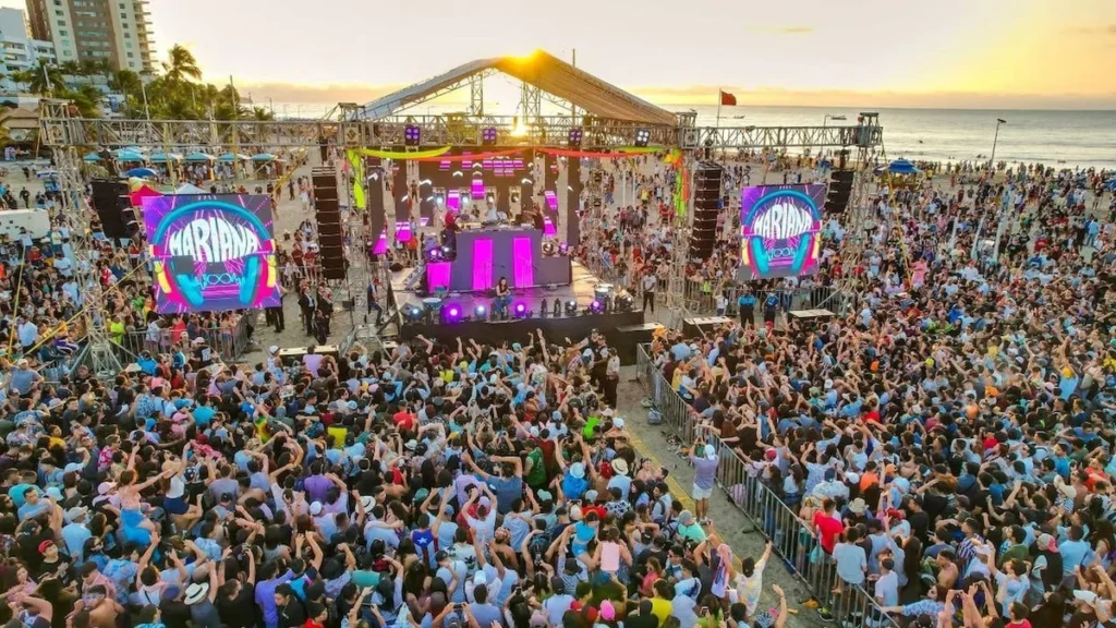 Escenario playero con luces y multitud durante festival de música en Manta