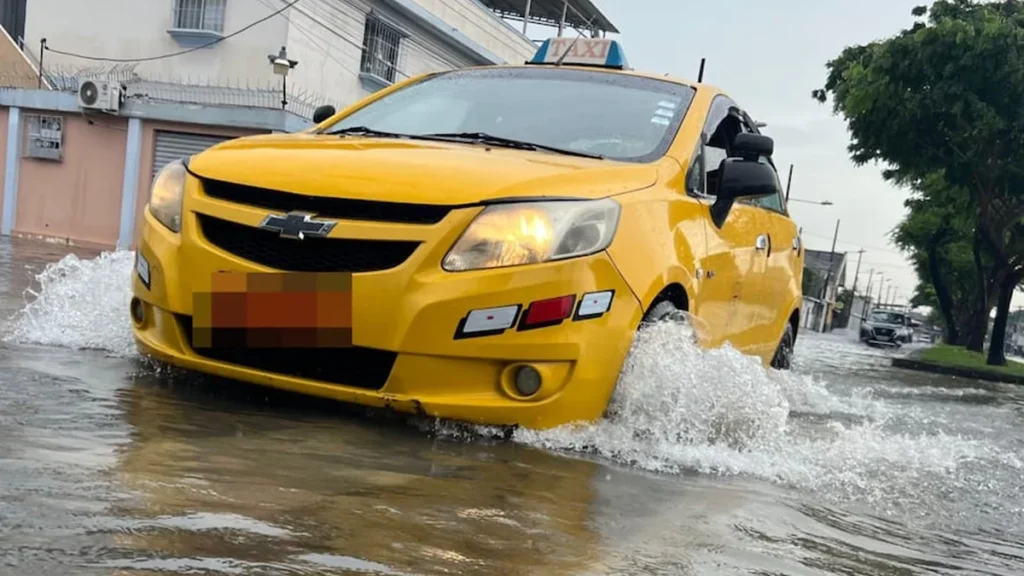 Avenida de Guayaquil con acumulación de agua de lluvia y tráfico vehicular lento