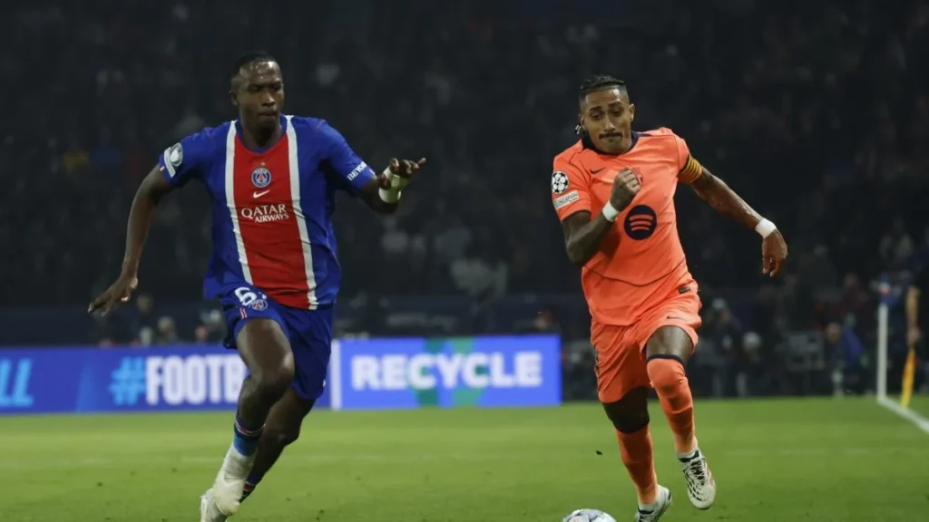 Willian Pacho marcando a Raphinha en el partido de Champions League entre PSG y FC Barcelona