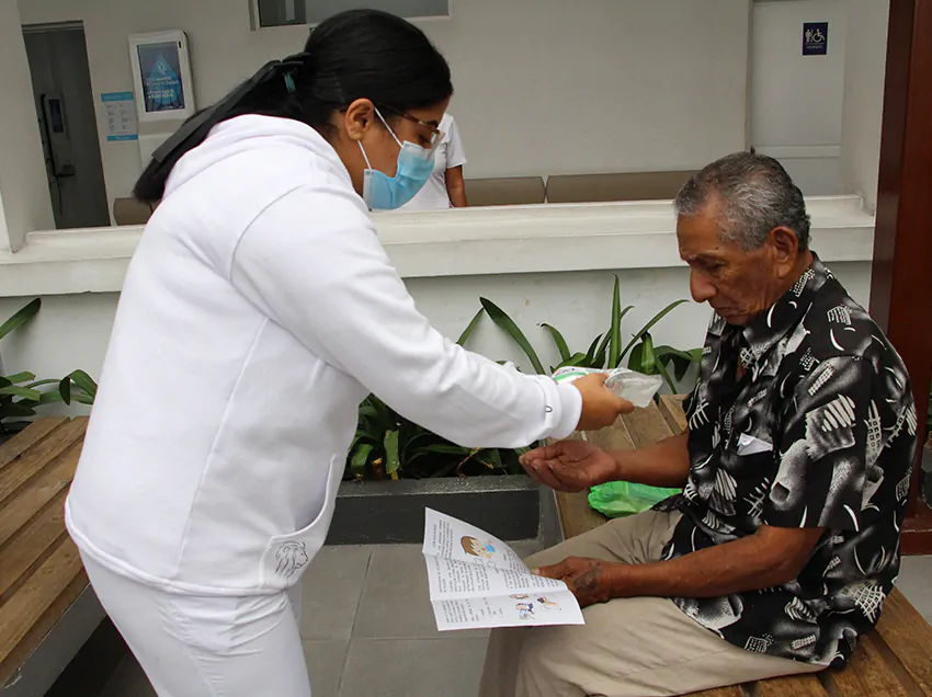 Personal médico del Hospital Bicentenario de Guayaquil entrega información preventiva sobre la tosferina y fiebre amarilla a un paciente adulto mayor.